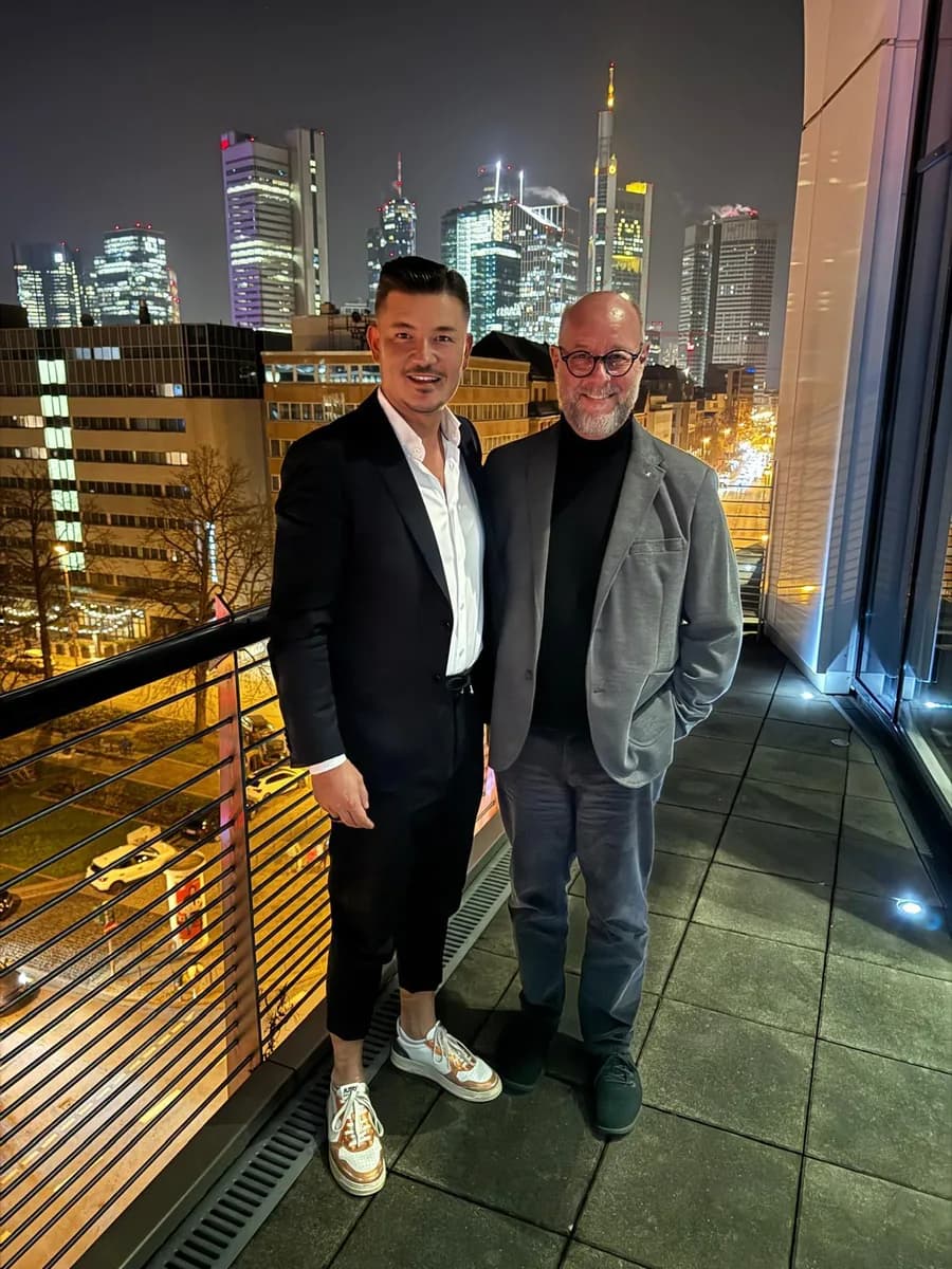 Selmir Suljkanovic und Jürgen Hohnen auf einer Dachterrasse mit Blick auf die Frankfurter Skyline